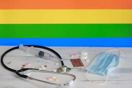 LGBT flag on the background of pills, stethoscop e an d medical mas kon the table. The flag of sexual minorities and medical suppliesの写真素材