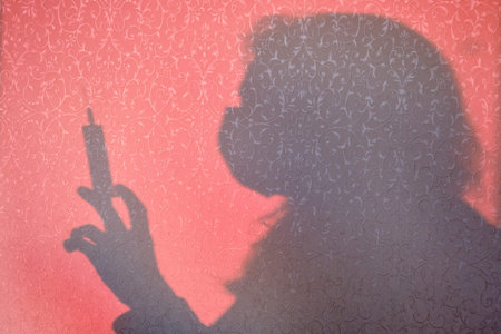 Shadow of a woman silhouette on a syringe for injection. Protection against covid-19 coronavirus...