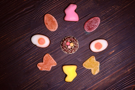 Candy for Easter in the form of a rabbit made of marmalade and chocolate eggs on a dark background