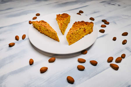 Brownies with nuts on wooden white background. Almonds on a light wooden table. Pieces of almond pie on a large plate.の写真素材