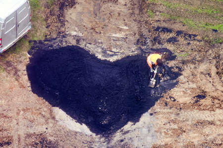 Road worker lays new asphalt in the shape of a heart, top viewの写真素材