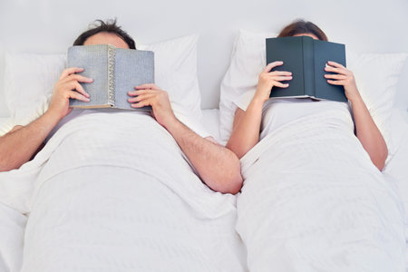 The husband and wife fell asleep covered with books lying in a white bed. Relationship problems...