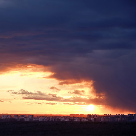 Cloudy sky over the houses during the orange sunset