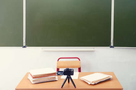 Teacher desk, blackboard and a video camera filming an online lesson, no people. Empty school table, nobodyの写真素材