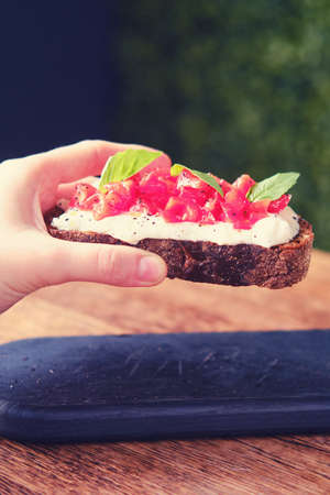 Hand holds bruschetta on a tray in a cafe, italian snack close upの写真素材
