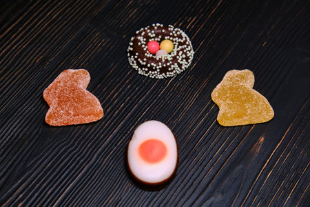 Candy for Easter in the form of a rabbit made of marmalade and chocolate eggs on a dark background
