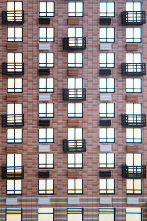 Wall of a brown house with luminous windows, background. Closeup of the facade of the buildingの写真素材