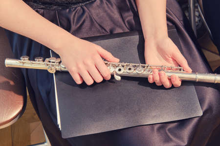 Young woman holding a flute in her hands, close-upの写真素材