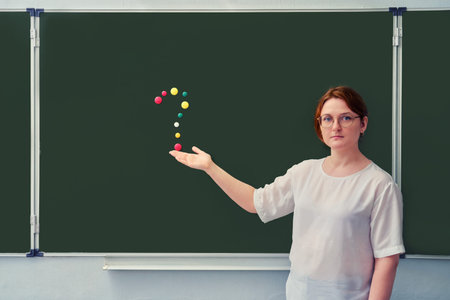 A school teacher and a question mark made of magnets on a blackboard, copy space