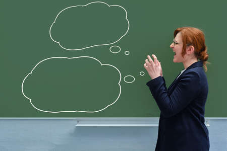 School teacher screaming evil against a green blackboard, copy spaceの写真素材