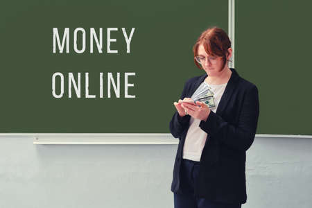 Business man counts US dollars at the school board with the inscription "Money online"の写真素材