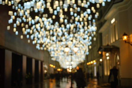 Blurred background, night street with festive lights and walking people.