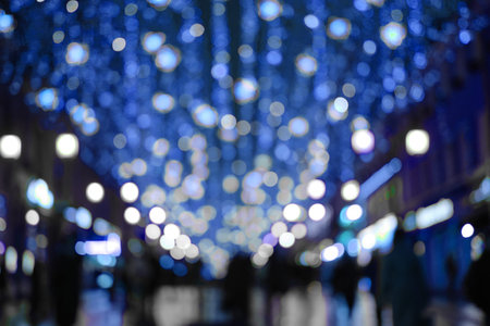 Blurred abstract background, bokeh in night street with festive lights and walking people