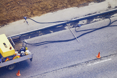 Jackhammers are lying on the road and sidewalk unattended, top view