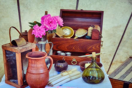 Ancient decor of life of 18-19 centuries. Table with candles, lamp, food, flowers, dishes and vase. Vintage style dwelling of the past.の写真素材