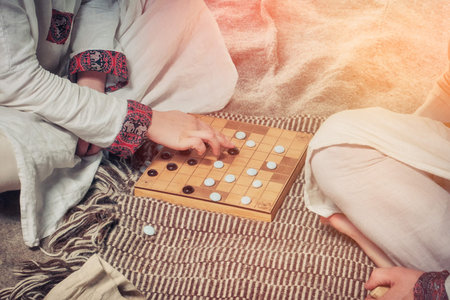 Tafl is a Scandinavian boardgame. Players at the Board game a retro style. Two men playing...