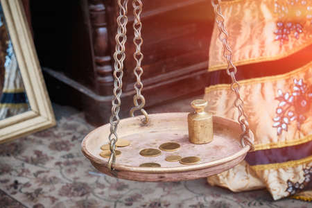 Retro money with a weight on the scale. Large scale bowl hanging on chains. Ancient interior inside the house.の写真素材