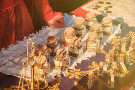 Ancient shop of a seller of spices at the historic fair. The hands of the seller of spice on the retro marketの写真素材