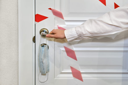 A hand opens a closed door with a stop tape, the concept of the end coronavirus epidemic