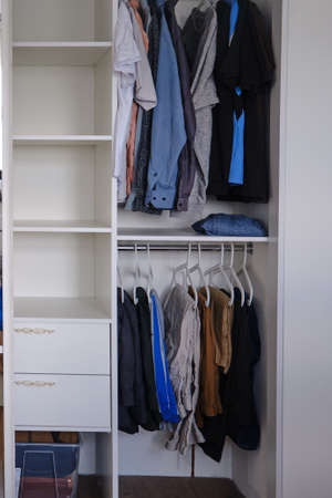 Wardrobe section with hanging things and clothesの写真素材