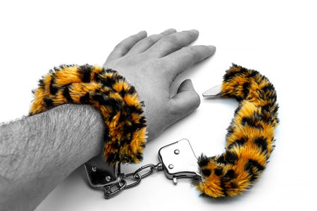 Soft BDSM bandage on the guy's arm. White background, isolate. Hand shackled with soft handcuffs,...