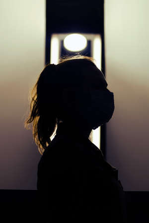 Silhouette of a female nurse in a medical mask on her faceの写真素材