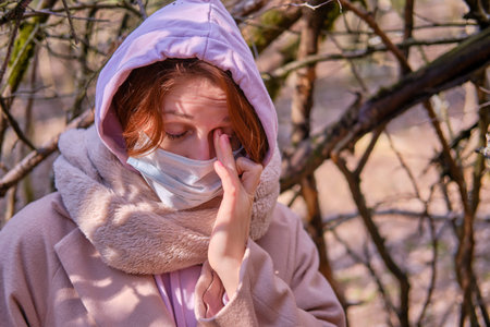 A woman in a medical mask is crying in depression while standing in a shelter, forest. Tourist...