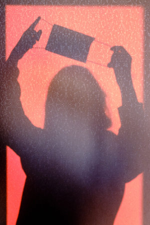 Shadow of a woman putting on a protective medical mask. Protection against covid-19 coronavirus...