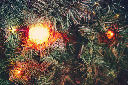 Lantern on the background of branches of a Christmas tree covered with snow, background. Yellow lamp in fir branches in the snow, copy spaceの写真素材