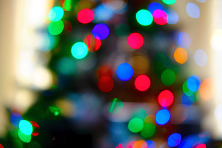 Background of blurred christmas tree in green and red light of garlands, balls and decorations for...