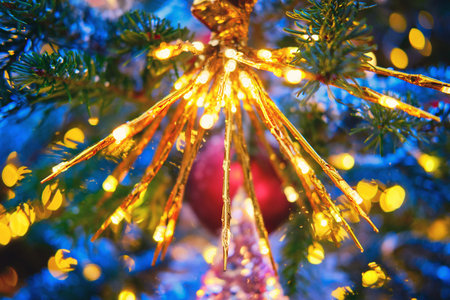 Yellow lantern hanging as decoration on green Christmas tree, close-up, flashlightの写真素材