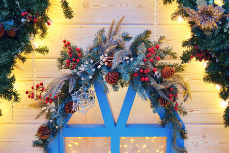 Window of a wooden house decorated with branches of a Christmas tree and mistletoe. Ornament for the celebration of new year and Christmasの写真素材