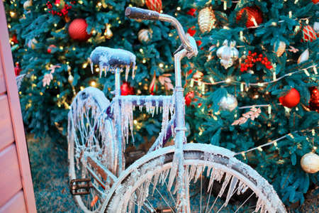 Icy bike on the background of a Christmas tree with a bauble near the house, new yearの写真素材
