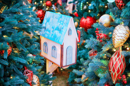 Christmas tree with a decorative mailbox in the form of a house. Glass toys and balls as a yard decoration in the new yearの写真素材