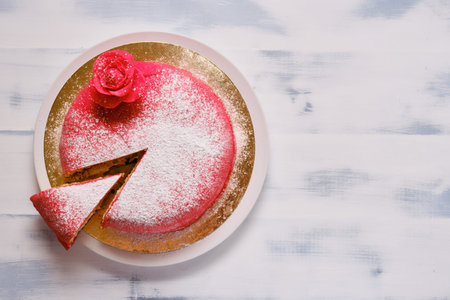 Red cake covered with marzipan or mastic with a cut piece, copy space