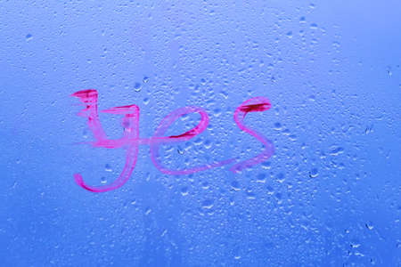 On the window pane it says "Yes." Glass with water drops on an autumn windowの写真素材