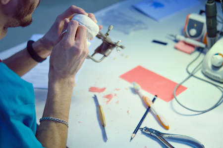 The dentist's hands are working on making denture to replace the patientの写真素材