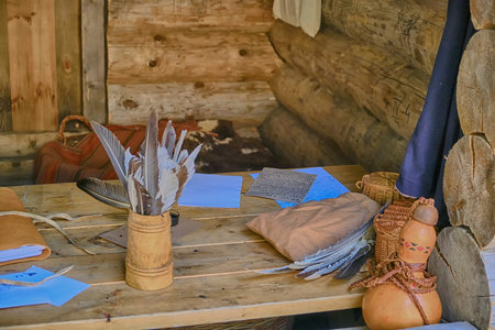 Table with writing utensils in retro style. Feathers, ink and paper in a wooden house.