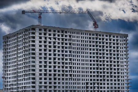 Multi-storey building and tower cranes close-up. Construction of the building against a stormy sky and clouds.の写真素材