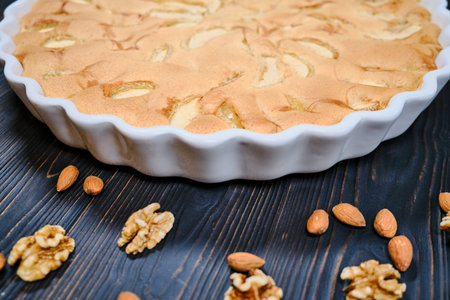 Homemade cake ripe apples on dark wooden background. Apple pie with nuts close-up. Fruit pie with...