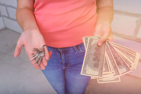 A young woman with dollars in her hands thinking about the repair of a new apartment.の写真素材