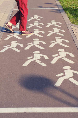 Woman crosses a bike path in a park at a pedestrian crossingの写真素材