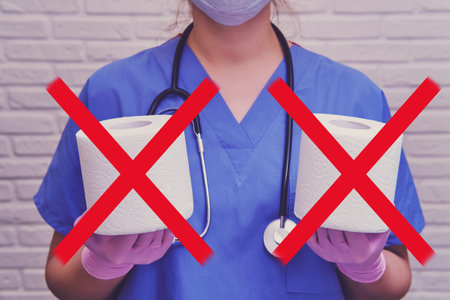 A doctor in protective gloves holds crossed-out rolls of toilet paper, the concept of diarrhea