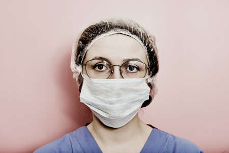 Woman doctor on a gray background. Concept of the fight against coronavirus. Face woman nurse in a blue uniform.の写真素材