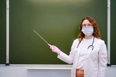 School doctor shows a pointer to a blank chalkboard, copy spaceの写真素材