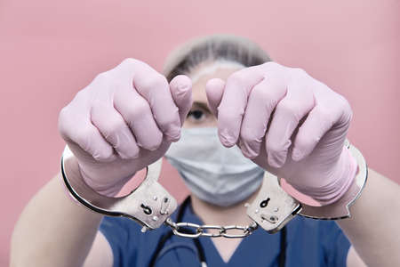 The doctor holds out his handcuffed hands. Call stay home for people.の写真素材