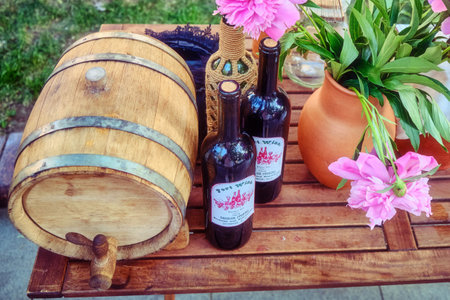 Moscow \ Russia 06 07 2019: Wooden barrel, flowers and wine bottles with a retro style label. American wine of the conquest of the wild West - PortWine, George Storm, Hudson NYのeditorial素材
