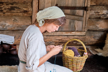 Moscow \ Russia 06 10 2019: Woman knitting wool lying in a basket. Retro fashion knitting yarn and wooden knitting needles. Wooden house and clothes in vintage style.のeditorial素材