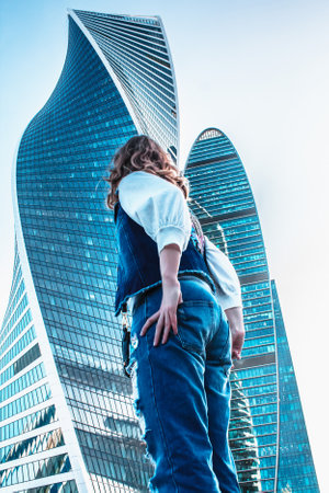 Moscow / Russia - AUGUST 18, 2018: girl stand of the business center. Woman in jeans near office buildings. Glass skyscrapers on a Sunny day. Corporate business center in summer midst of work.のeditorial素材