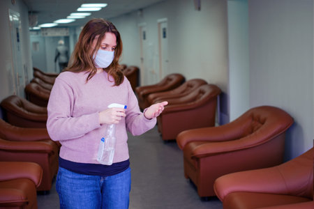 A patient with a sanitizer disinfects his hands while standing in the hospital corridor